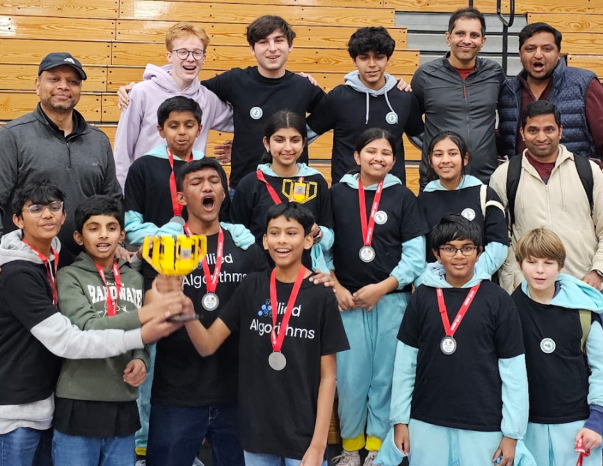 Two Wilton, Connecticut robotics teams in matching shirts, wearing medals and holding up a LEGO-built trophy